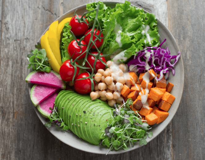 high fibre, colourful salad bowl with tomatoes, avocado, chickpeas, sweet potato, cabbage and lettuce.
