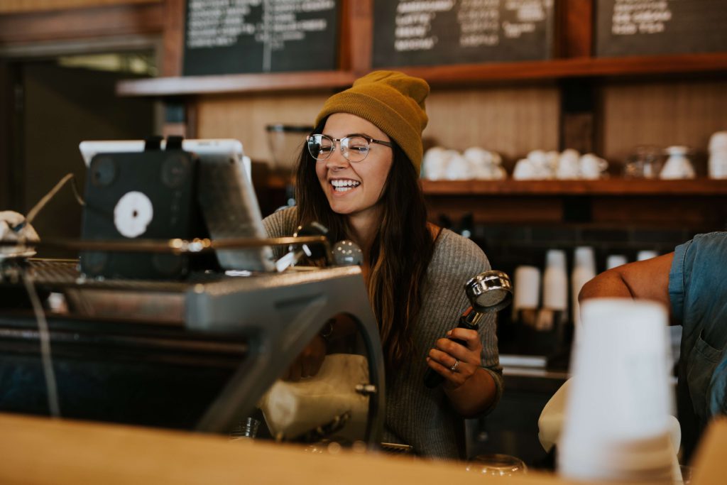 smiling female barista behind a coffee  machine