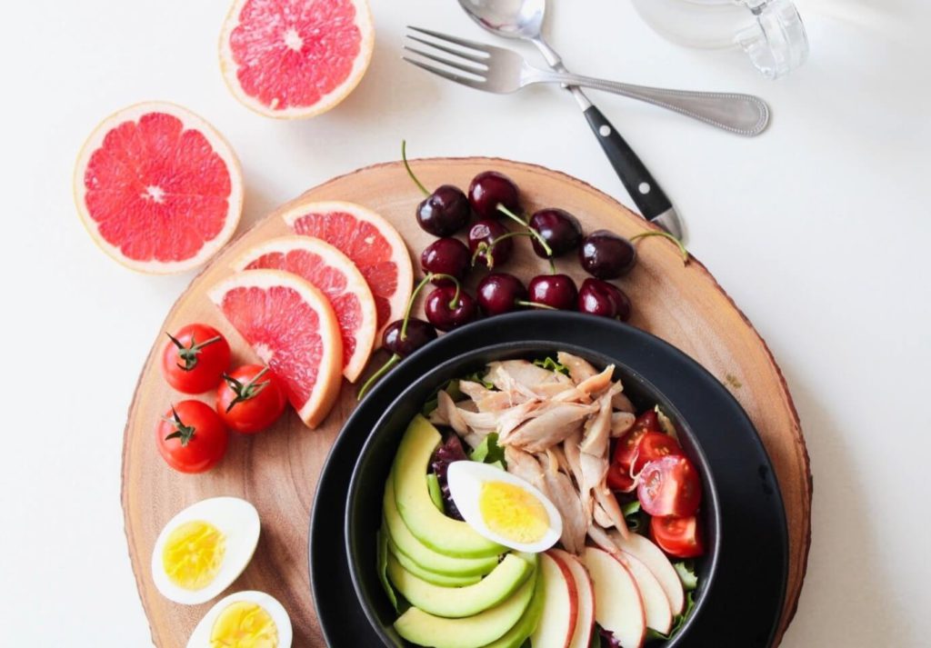 nicely presented healthy meal consisting of fruits, vegetables, eggs and meat.