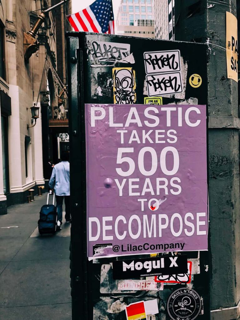 purple sign pasted on a black lamp post saying 'plastic takes 500 years to decompose'