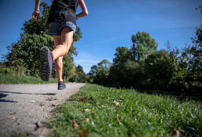 slim woman running along a path in a park