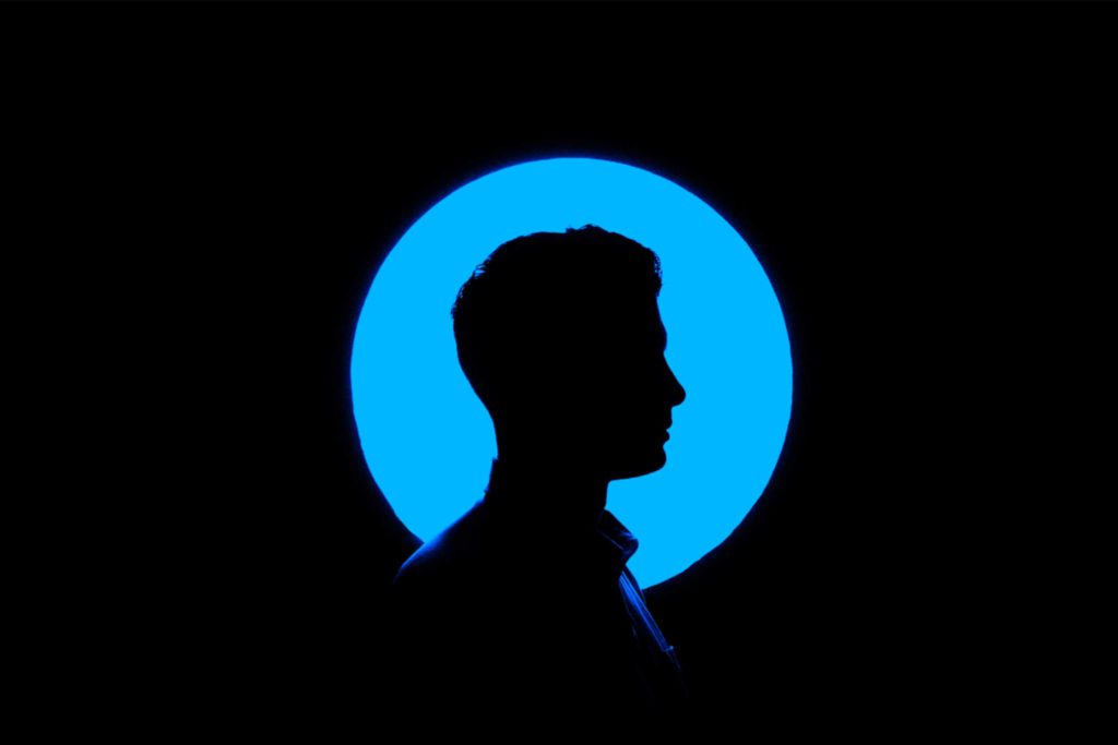 silhouette of a man against a circular blue light