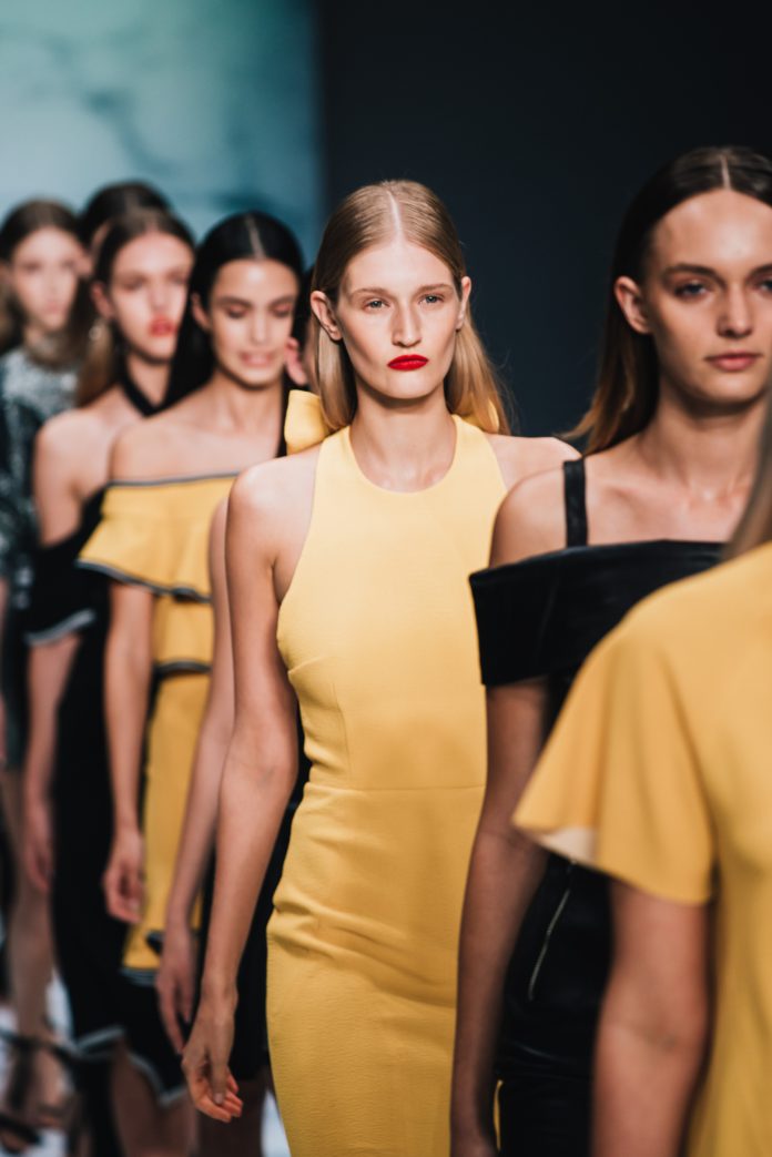 models wearing yellow walking down a catwalk at fashion week