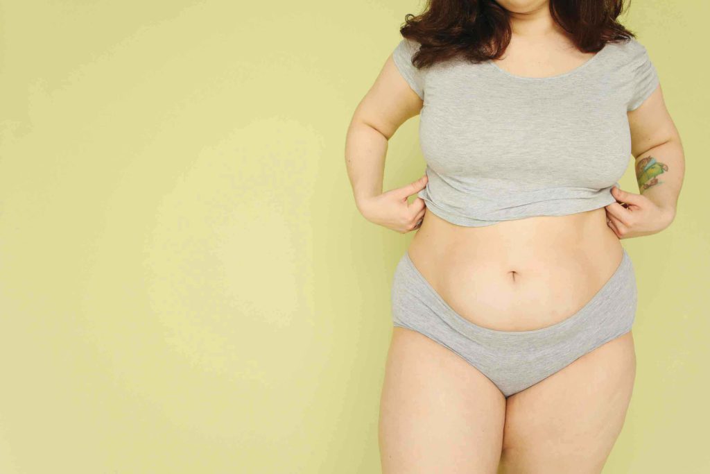 shapely woman in grey underwear against a greeny-yellow background showing that beauty comes in all shapes and sizes.